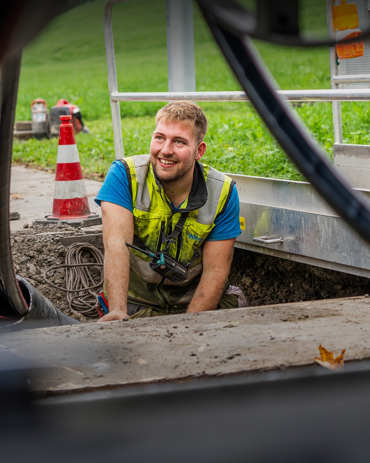 Junger WWZ-Mitarbeiter hockt in Loch und tätigt Stromarbeiten.